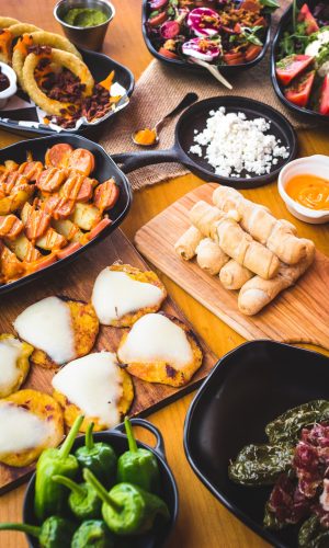 Close-up of plate with nacho chips in dressing served with various snacks on table.